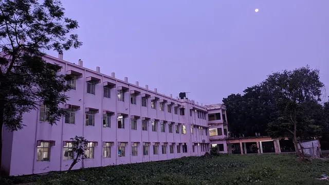 সন্ধ্যার আকাশের নিচে রাজশাহী মেডিকেল কলেজ হাসপাতালের একটি ভবন; সামনে সবুজ ঘাসের মাঠ।